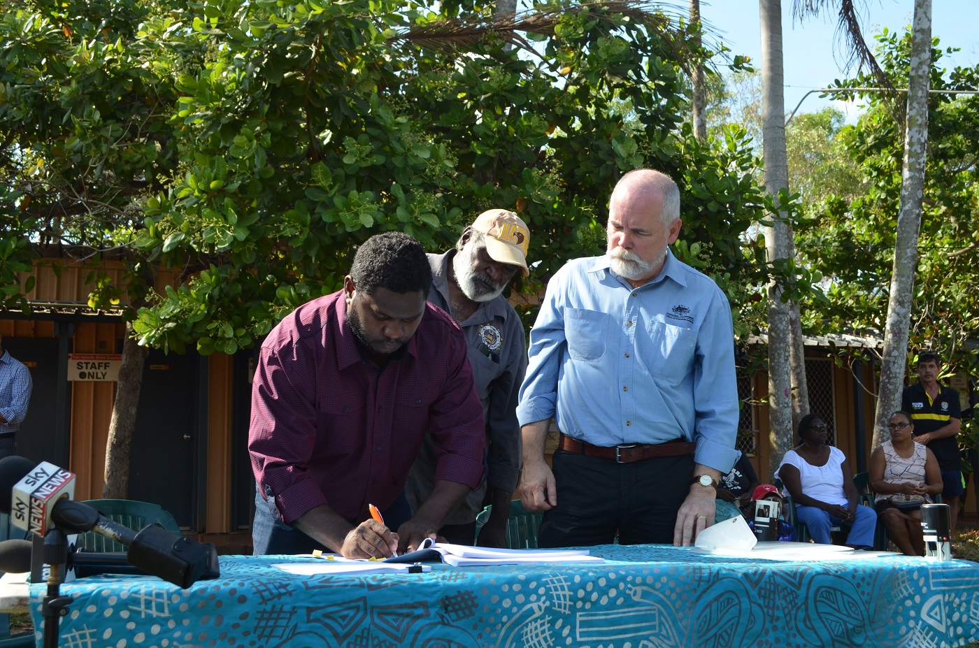 Signatories of the Tiwi Land Trust sign the Pirlangimpi Township lease as Greg Roche, Executive Director of Township Leasing looks on