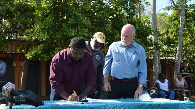 Signatories of the Tiwi Land Trust sign the Pirlangimpi Township lease as Greg Roche, Executive Director of Township Leasing looks on